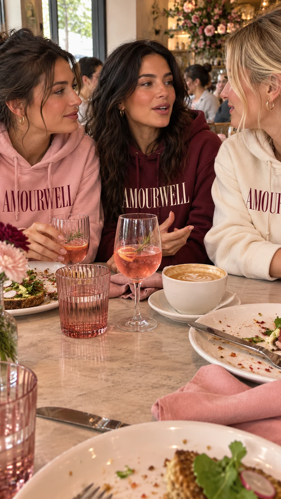 Friends talking over brunch in Amourwell hoodies